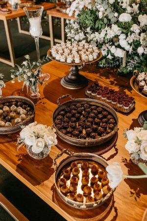 Téléchargez les photos : Savoureux biscuits et bouquets de cerises au chocolat noir sur une table en bois lors d'une fête de mariage, plan vertical - en image libre de droit