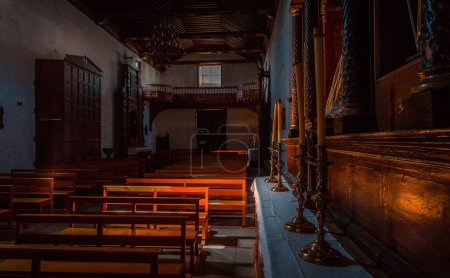 Foto de El interior de la Iglesia de San Pedro en Vilaflor con la entrada y bancos en tonos oscuros - Imagen libre de derechos