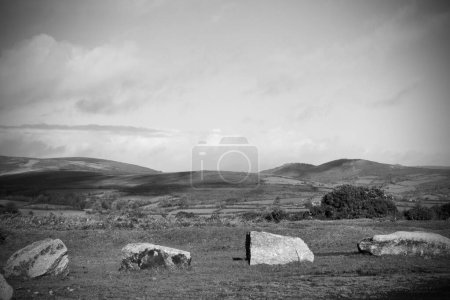 Téléchargez les photos : Une échelle de gris de gros rochers sur le sol avec les belles montagnes et collines en arrière-plan - en image libre de droit