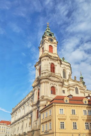 A vertical low angle shot of the historic St. Nicholas Church against a bright blue sky in Prague