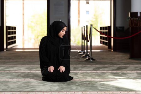 Photo for A beautiful Muslim woman in a mosque wearing a black dress with hijab. Muslim faith, culture. - Royalty Free Image
