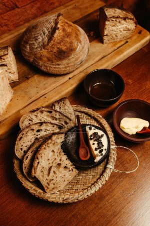 Téléchargez les photos : Un plan grand angle de pain croûté frais cuit au four et tranché servi sur une plaque de paille sur la table - en image libre de droit