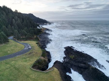 Foto de Una vista panorámica de las olas del mar agitadas que lavan los acantilados rocosos en Oregon contra un cielo sombrío - Imagen libre de derechos