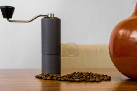 Téléchargez les photos : Un moulin à café manuel et des grains de café répartis sur une table en bois - en image libre de droit
