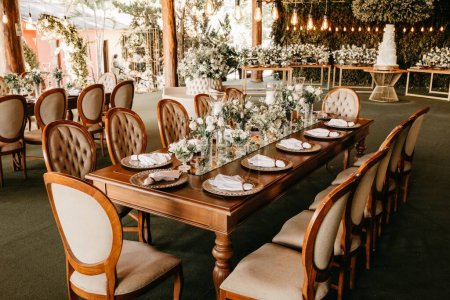 Foto de Un salón de lujo con mesas, asientos y ramos decorados en mesas bajo techo de madera - Imagen libre de derechos