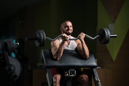 Téléchargez les photos : Un homme de bonne apparence caucasien faisant de l'exercice de poids avec haltères formation Dans Gym - en image libre de droit