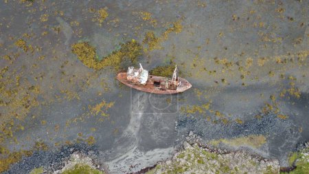 Téléchargez les photos : Un drone tiré d'un navire abandonné sur une île de la côte verte mousseuse au bord de la mer - en image libre de droit