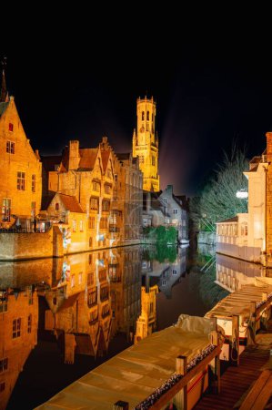 Téléchargez les photos : Vue verticale des vieux bâtiments traditionnels qui se reflètent dans l'eau la nuit à Bruges, Belgique - en image libre de droit