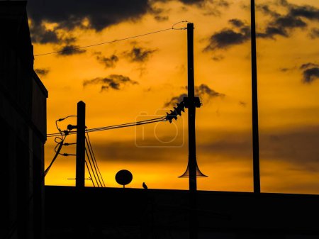Téléchargez les photos : Un beau ciel doré couchant sur la silhouette des poteaux électriques. - en image libre de droit