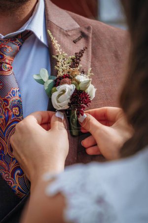 Photo for A female hands adjust the boutonniere on the jacket - Royalty Free Image