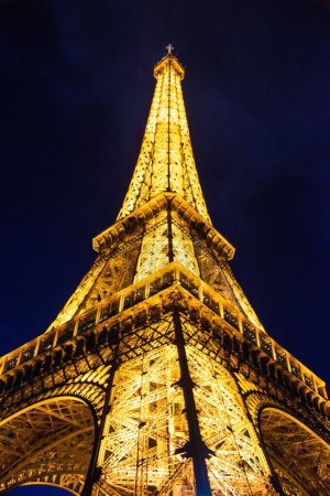 Téléchargez les photos : Vue verticale basse de la tour Eiffel en soirée avec lumières allumées, à Paris France - en image libre de droit