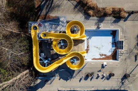 Téléchargez les photos : Un drone d'une piscine vide et un toboggan courbé jaune par une journée ensoleillée à Long Island, New York, USA - en image libre de droit