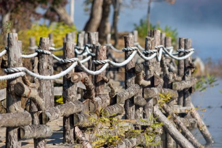 Téléchargez les photos : Une clôture en bois et une chaussée près de l'eau avec un fond flou. - en image libre de droit