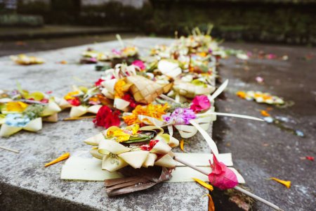 Téléchargez les photos : Un gros plan d'offrandes de fleurs couchées sur une surface de granit dans un temple à Bali - en image libre de droit