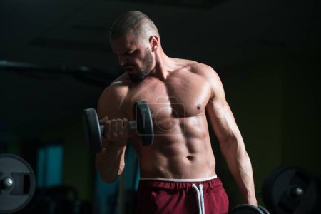 Foto de Un hombre atractivo de buen aspecto caucásico que hace ejercicio Peso con pesas que entrenan en gimnasio - Imagen libre de derechos