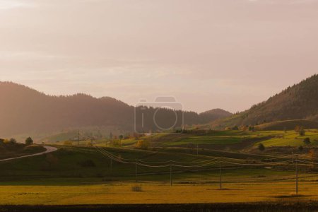 Photo for Fields with power lines and stations around, misty mountains, and sky in the background - Royalty Free Image