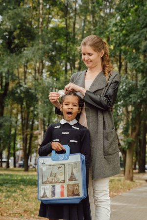 Téléchargez les photos : Plan vertical d'une petite fille hispano-biélorusse allant à l'école avec sa mère - en image libre de droit