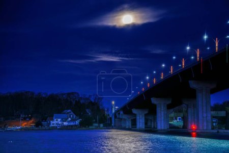 Photo for An evening view of a bridge over a calm coast under a bright moon - Royalty Free Image