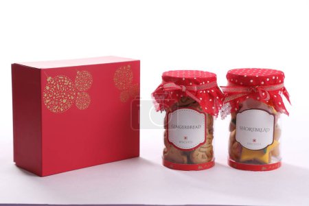 Photo for A closeup of two jars filled with Christmas Shortbread biscuits covered with a red cloth with a box - Royalty Free Image