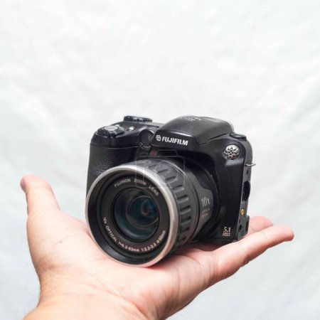 Foto de Un primer plano de una cámara compacta Fujifilm Finepix s5200 en la palma de una persona - Imagen libre de derechos