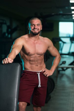 Foto de Un apuesto hombre joven caucásico y atractivo con cuerpo muscular relajante en el gimnasio - Imagen libre de derechos
