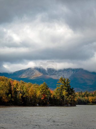 Téléchargez les photos : Une vue verticale de Baxter Peak vue entourée d'une forêt verte sur le lac Katahdin, dans le Maine, au début de l'automne, par une journée nuageuse - en image libre de droit