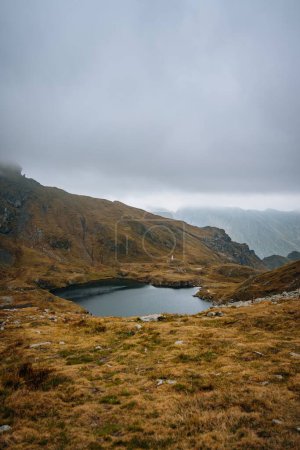 Photo for The beautiful small Capra Lake in Romania surrounded by the big mountains under the gloomy sky - Royalty Free Image