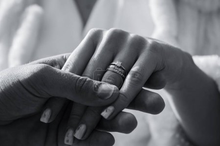Téléchargez les photos : Gros plan en niveaux de gris d'un homme tenant la main d'une femme avec une bague de fiançailles à son doigt - en image libre de droit