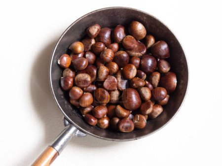 Photo for Picture taken from above with lots of sweet chestnuts in a roasting pan  with white background - Royalty Free Image