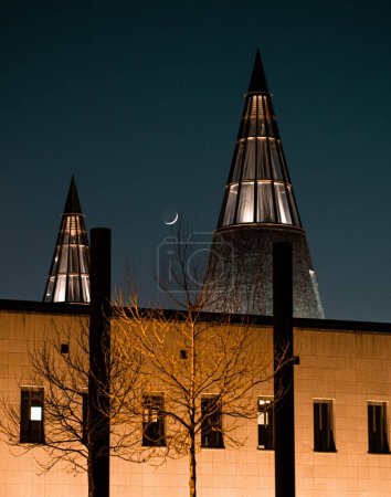 Téléchargez les photos : Vue de nuit verticale du croissant de lune au-dessus d'une salle de musée avec deux cônes lumineux pointus à Bonn, en Allemagne - en image libre de droit