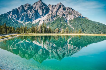 Téléchargez les photos : Une vue panoramique d'un lac à côté d'une route avec le reflet de la montagne derrière visible sur l'eau - en image libre de droit