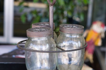 Foto de Un primer plano de frascos de vidrio vacíos en un soporte de metal. Frascos en una tienda de antigüedades, California. - Imagen libre de derechos