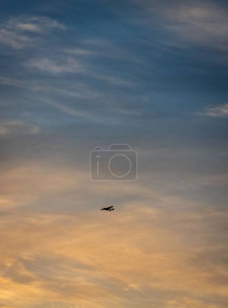 Téléchargez les photos : Plan vertical d'un avion volant dans le ciel avec des nuages au coucher du soleil. - en image libre de droit