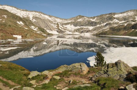 Foto de Una hermosa vista de un lago sereno rodeado de campos nevados y montañas en los Pirineos Catalanes - Imagen libre de derechos