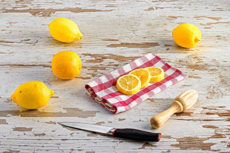 Foto de Un cuchillo, limones y un exprimidor de limón olivewood en una mesa de madera - Imagen libre de derechos