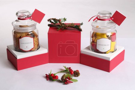 Téléchargez les photos : Un gros plan de bocaux remplis de biscuits de Noël recouverts d'un tissu rouge à l'intérieur de deux boîtes - en image libre de droit