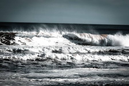 Foto de Un primer plano de las olas espumantes del océano rodando arena en tierra durante el día - Imagen libre de derechos