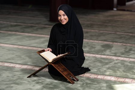 Photo for A beautiful Muslim woman in a mosque reading Quran. Muslim faith, culture. - Royalty Free Image