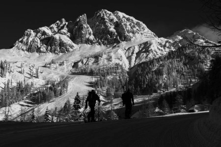 Photo for A grayscale beautiful view of skiers on a snowy mountain during sunrise - Royalty Free Image