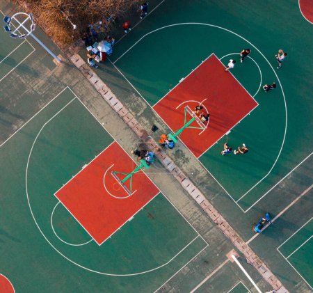Téléchargez les photos : Une vue aérienne supérieure de deux terrains de basket-ball séparés et des jeunes qui jouent le jeu - en image libre de droit