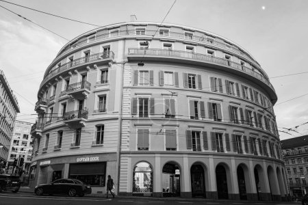 Téléchargez les photos : Une échelle de gris d'un bâtiment rond au centre-ville de Lausanne en Suisse avec des voitures et des personnes qui passent - en image libre de droit