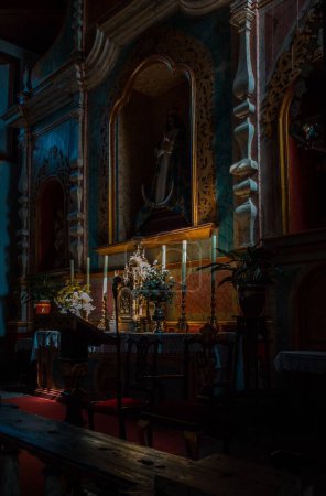 Foto de El altar de la Iglesia de San Pedro en Vilaflor con las estatuas y velas en tonos oscuros - Imagen libre de derechos