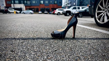 Téléchargez les photos : Un gros plan d'une chaussure à talons hauts noire dans un parking - en image libre de droit