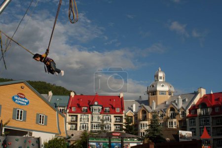 Foto de Los edificios de colores en Mont-Tremblant Quebec, Canadá y un niño, bungee saltar en el trampolín - Imagen libre de derechos