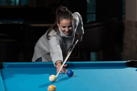 Photo for A closeup of a young woman playing billiards. - Royalty Free Image