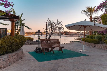 Téléchargez les photos : Un endroit calme avec banc et parasol dans un lagon à El Gouna au coucher du soleil - en image libre de droit