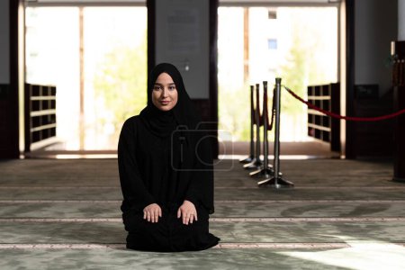 Photo for A beautiful Muslim woman in a mosque wearing a black dress with hijab. Muslim faith, culture. - Royalty Free Image