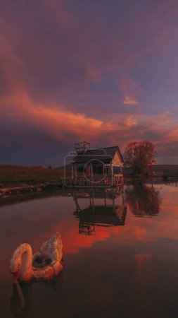 Photo for A vertical of a wooden building near lake view at sunset, purple, cloudy sky in the background - Royalty Free Image