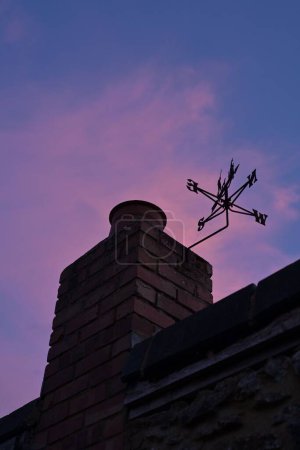 Téléchargez les photos : Plan à angle bas de la girouette montrant la direction de la cheminée près du coucher du soleil - en image libre de droit