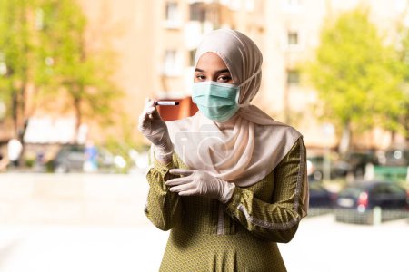 Téléchargez les photos : Une infirmière médecin musulmane portant un masque protecteur et des gants - Tenir un test sanguin de virus - en image libre de droit